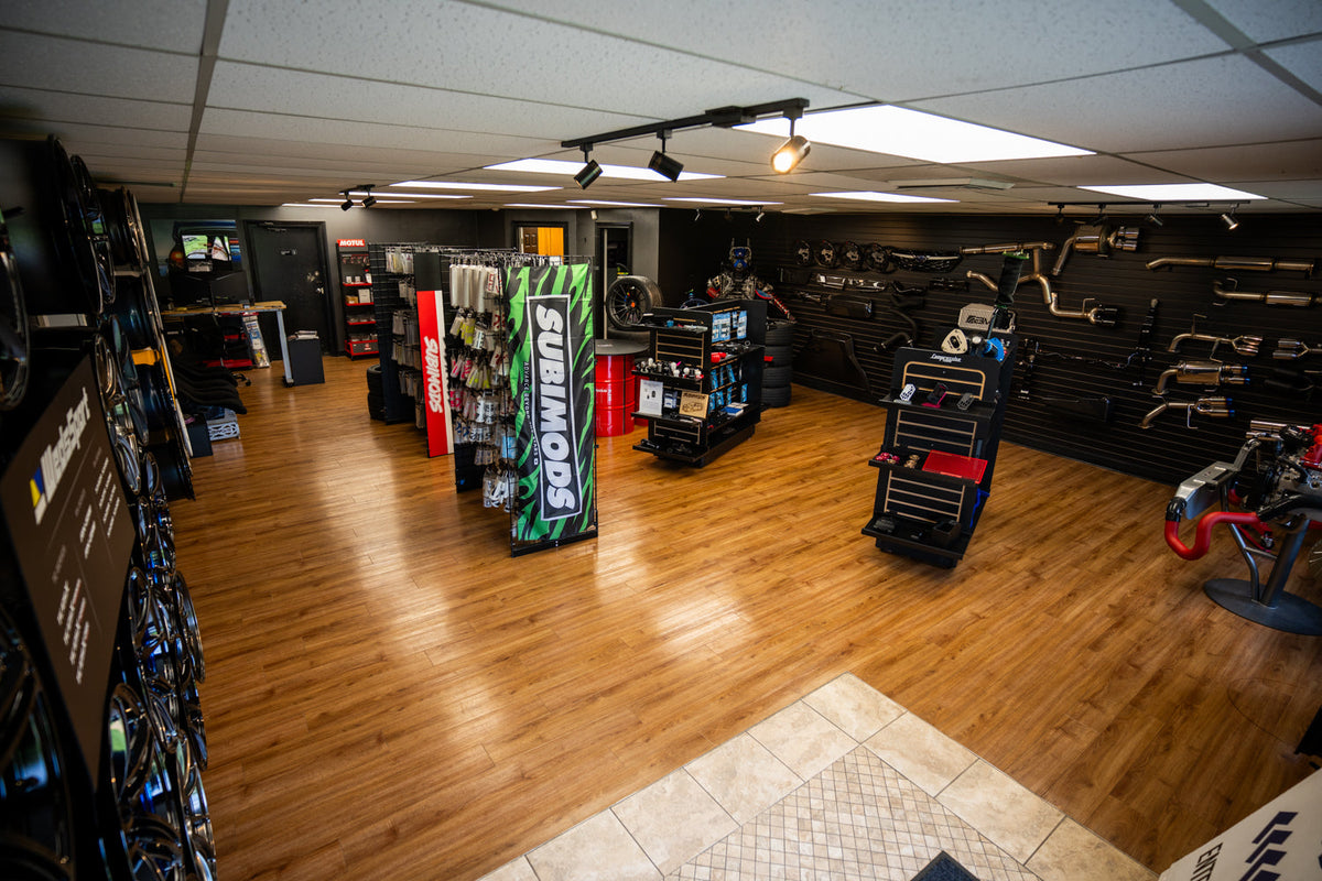 A wide view of the Subimods showroom with performance parts and wheels on display.