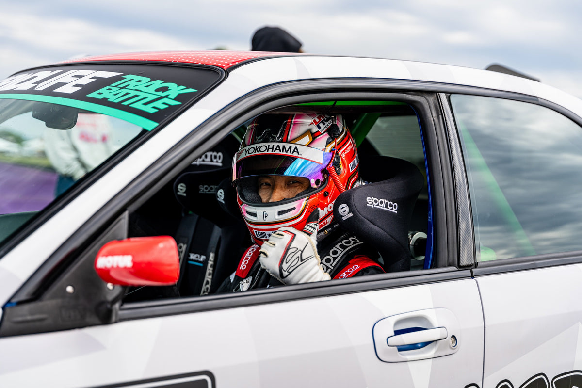 Dai Yoshihara wearing his helmet in the driver’s seat of his white Subimods Subaru at GRIDLIFE Midwest in 2026.